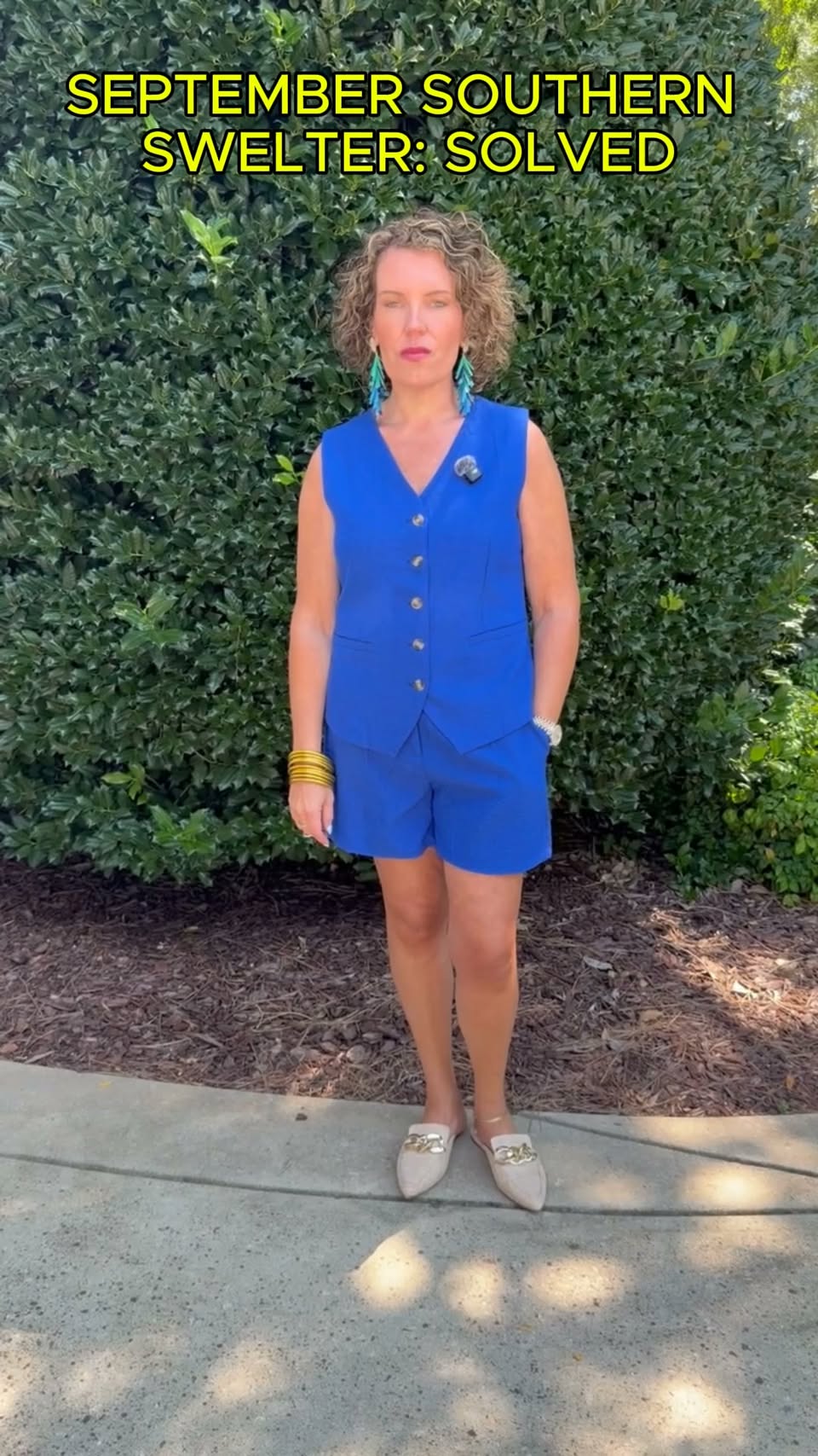 Jessica wearing a royal-blue two-piece vest outfit with statement earrings and backless mules